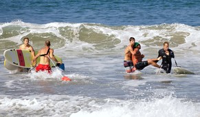 Rettungsschwimmer holen den verletzten Schwimmer aus dem Wasser.