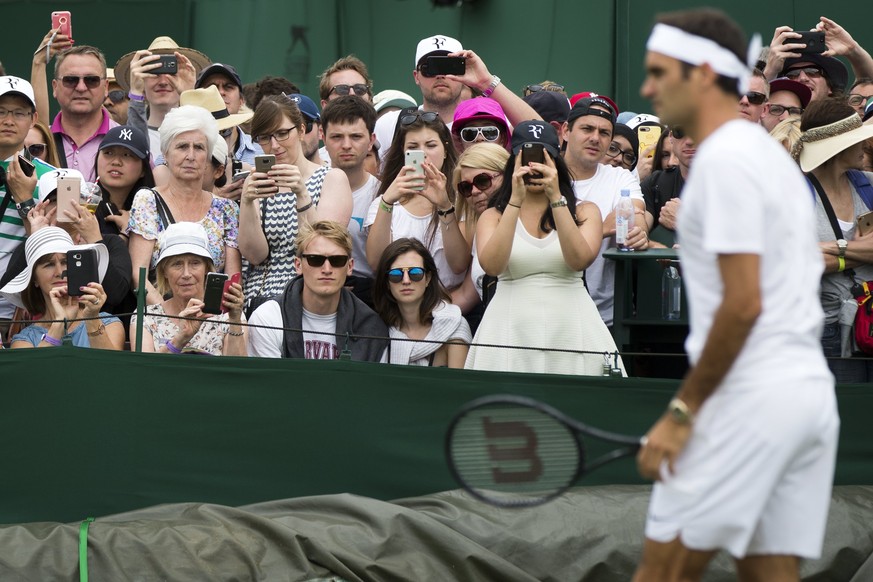 epa06065946 Tennis fans watch Roger Federer of Switzerland in action during a short training session prior to his first round match against Alexandr Dolgopolov of Ukraine, at the All England Lawn Tenn ...