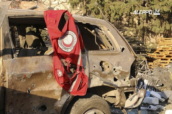 This image provided by the Syrian anti-government group Aleppo 24 news, shows a vest of the Syrian Arab Red Crescent hanging on a damaged vehicle, in Aleppo, Syria, Tuesday, Sept. 20, 2016. A U.N. hum ...