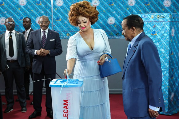 epa12448979 Cameroon President Paul Biya (R) watches his wife Chantal cast her vote during the presidential election in Yaounde, Cameroon, 12 October 2025. Twelve candidates are running in the preside ...