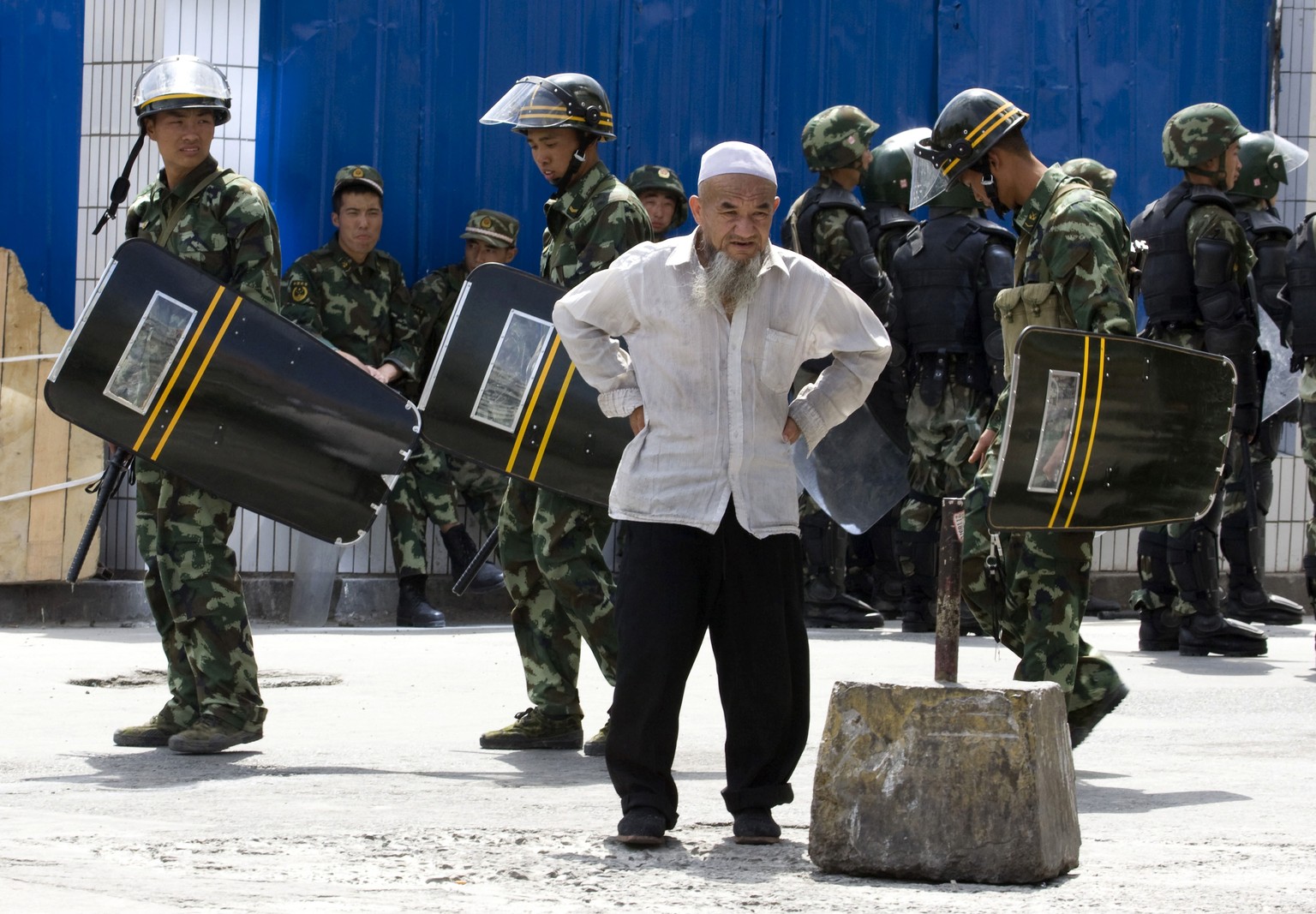 FILE - In this July 8, 2009, file photo, paramilitary police walk past an elderly ethnic minority man a day after Han Chinese mobs attacked Uighur in retaliation for earlier attacks in neighbourhoods in Urumqi, western China's Xinjiang region. Analysts say the Urumqi riots in 2009 set in motion the harsh security measures now in place across Xinjiang, where about 1 million Uighurs, Kazakhs and other Muslims are estimated to be held in heavily-guarded internment camps _ also called 