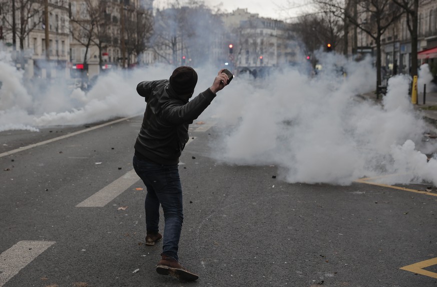 A demonstrator throws a stone toward police officers during a protest against the recent shooting at the Kurdish culture center in Paris, Saturday, Dec. 24, 2022. Kurdish activists, left-wing politici ...