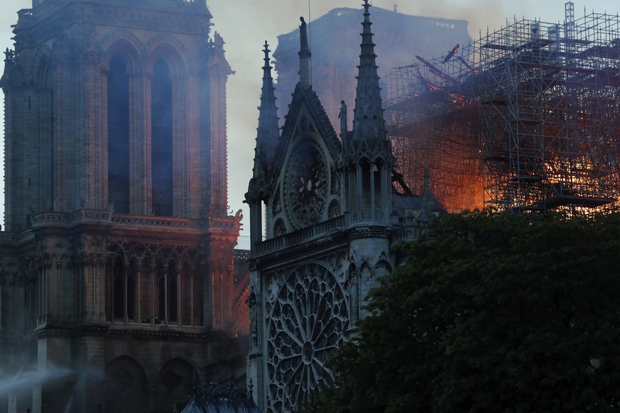 Firefighters tackle the blaze as flames and smoke rise from Notre Dame cathedral as it burns in Paris, Monday, April 15, 2019. Massive plumes of yellow brown smoke is filling the air above Notre Dame  ...