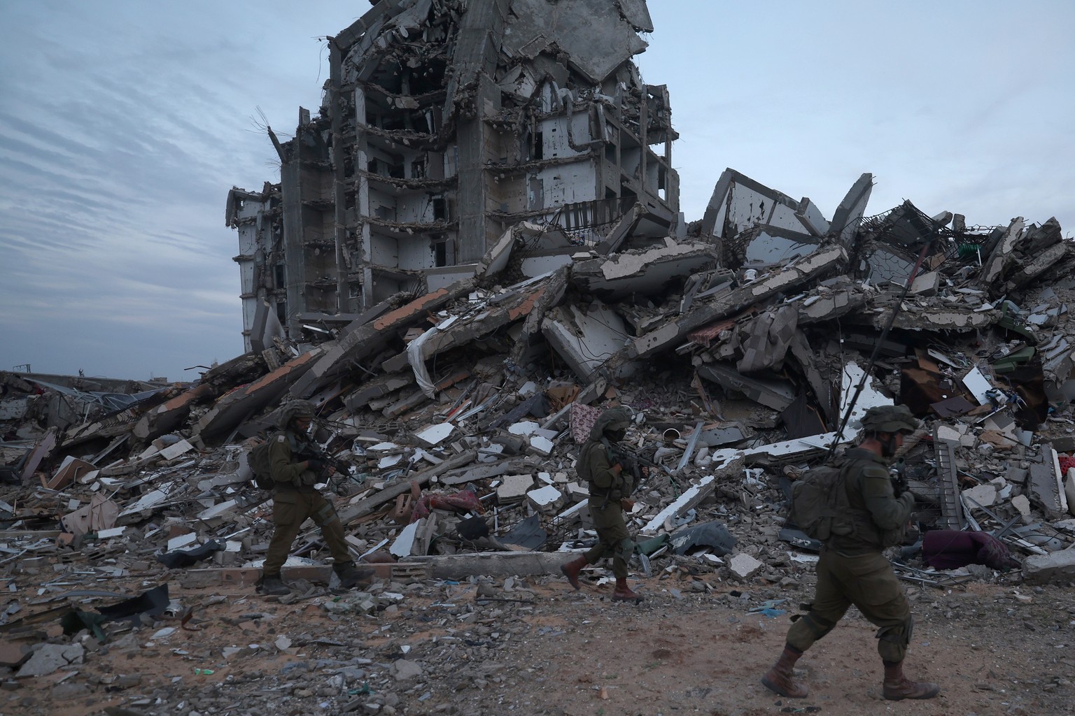 epa11018177 A photo taken while embedded with the Israel Defense Forces (IDF) shows Israeli soldiers walking past the rubble of destroyed buildings in the Palestinian town of Beit Lahia, on the outski ...