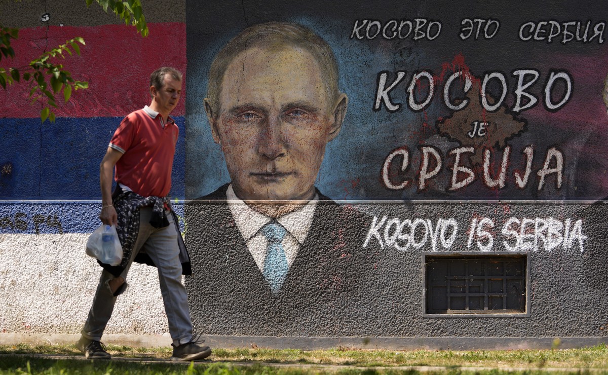 A man passes by graffiti depicting Russian President Vladimir Putin, reading: "Kosovo is Serbia" in Belgrade, Serbia, Monday, Aug. 1, 2022. Kosovo's authorities early Monday moved to ea ...