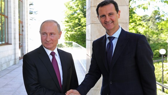 FILE - In this May 17, 2018, file photo, Russian President Vladimir Putin, left, shakes hands with Syrian President Bashar al-Assad during their meeting in the Black Sea resort of Sochi, Russia. Assad ...