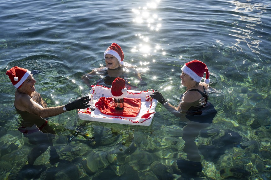 epaselect epa11042947 People swim with Santa hats in 8-degree water in Lake Leman, at Bains des Paquis on Christmas Eve, in Geneva, Switzerland, 24 December 2023. EPA/MARTIAL TREZZINI