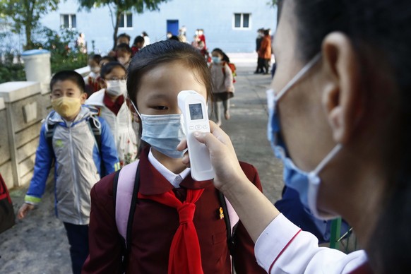 FILE - A teacher takes the body temperature of a schoolgirl to help curb the spread of the coronavirus before entering Kim Song Ju Primary School in Central District in Pyongyang, North Korea, on Oct. ...