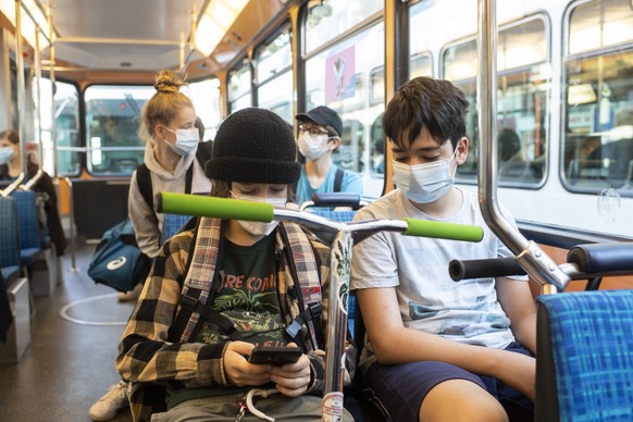 Zwei junge Maenner mit Atemschutzmaske fahren im Tram in Zuerich, aufgenommen am Montag, 6. Juli 2020. (KEYSTONE/Ennio Leanza)