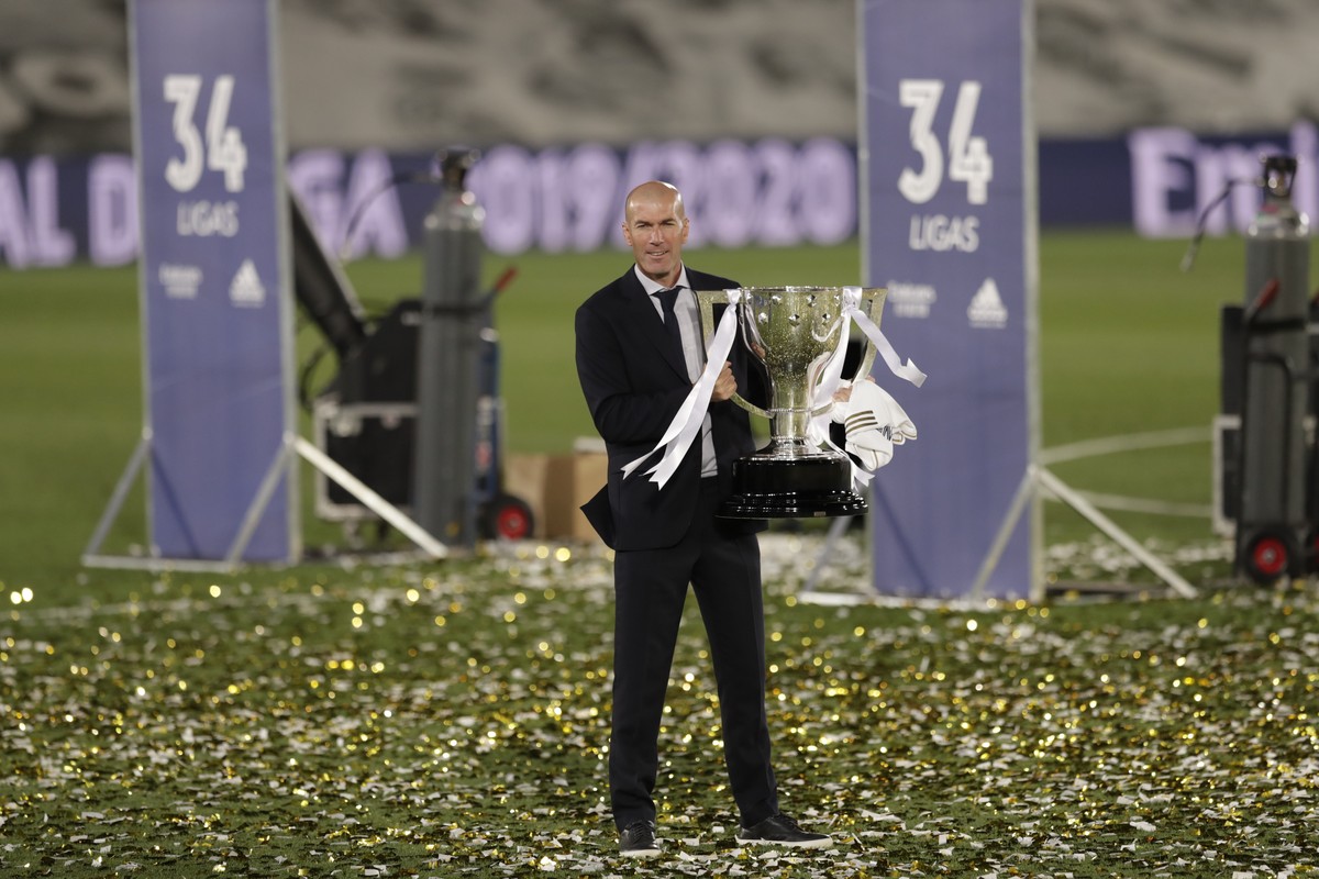 Real Madrid's head coach Zinedine Zidane, holds the trophy as he poses for the photographers after winning the Spanish La Liga 2019-2020 following a soccer match between Real Madrid and Villareal ...