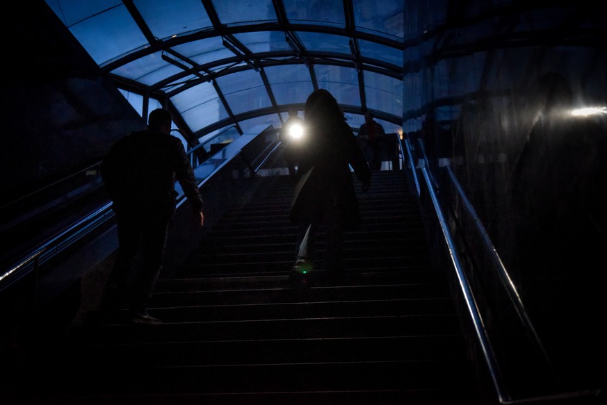epa10263391 People use light on their mobile phones in underground walkway during a power cut in Kyiv, Ukraine, 24 October 2022. Scheduled power cuts were introduced in Kyiv, power operator Ukrenergo  ...