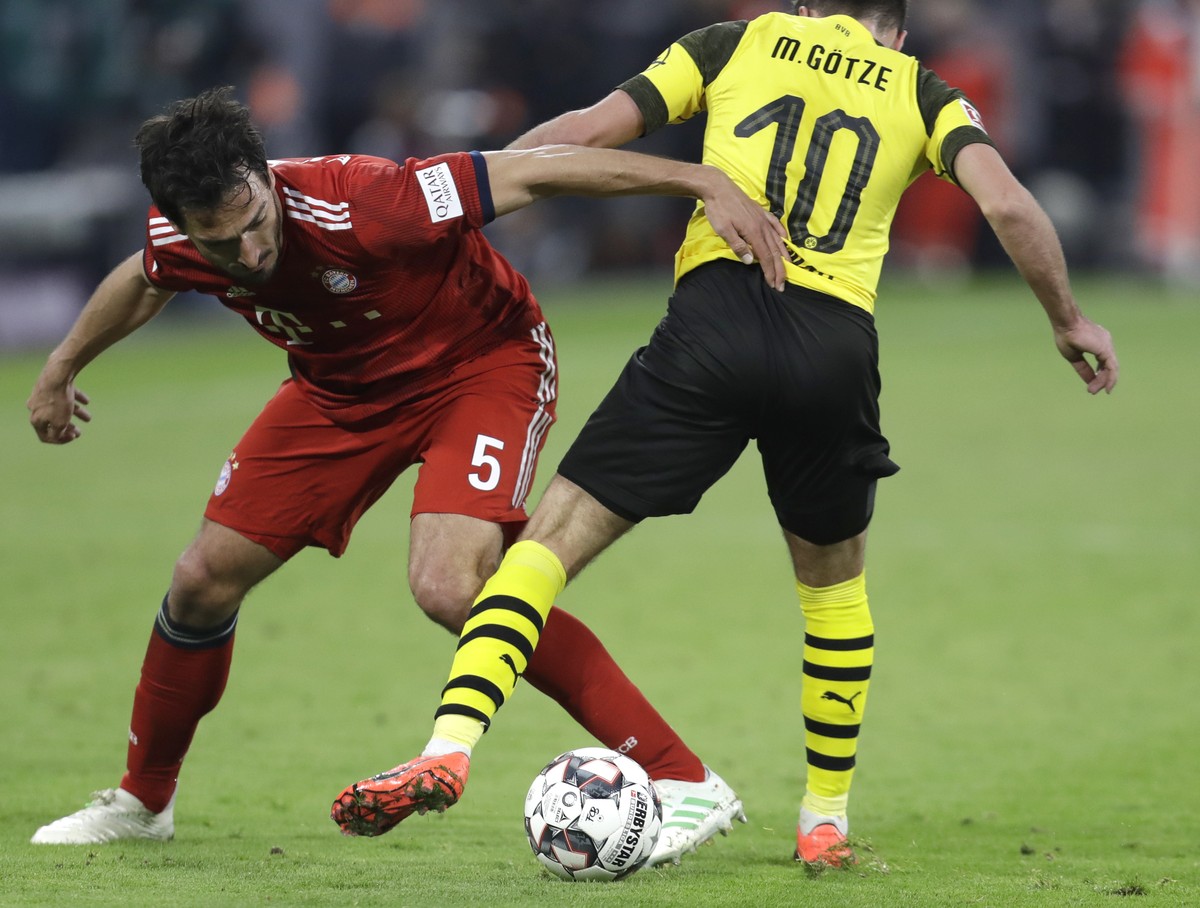 Bayern's Mats Hummels, left, and Dortmund's Mario Goetze challenge for the ball during a German Bundesliga soccer match between Bayern Munich and Borussia Dortmund in Munich, Germany, Saturd ...