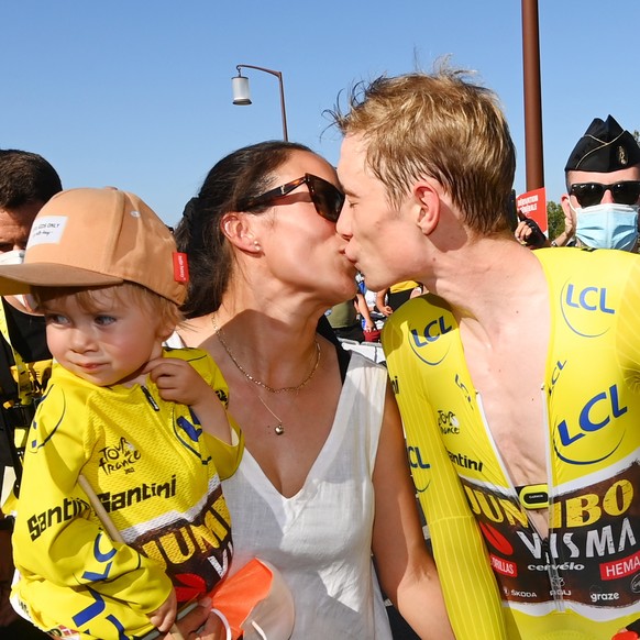 epa10088325 The Yellow Jersey Danish rider Jonas Vingegaard (R) of Jumbo Visma kisses his wife Trine Hansen (C) as she carries their daughter Frida (L) after crossing the finish line of the 20th stage ...