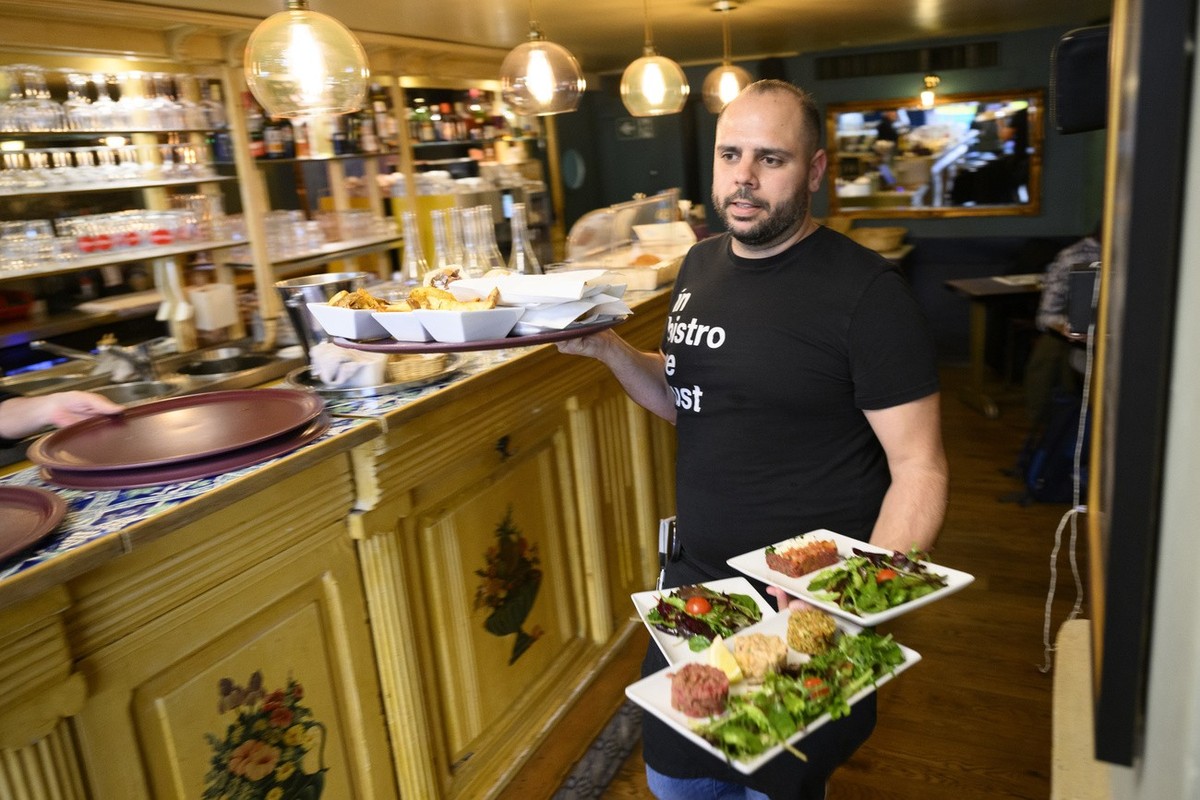 Un serveur sans masque de protection facial sert a manger a des clients dans le cafe restaurant salon le Java le jour de la levee des mesures pour lutter contre la pandemie de Coronavirus (Covid-19) c ...