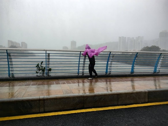 SANYA, CHINA - AUGUST 24: A local resident struggles to walk as Typhoon Kajiki brings strong winds and heavy rain on August 24, 2025 in Sanya, Hainan Province of China. Strong winds and heavy rain whi ...