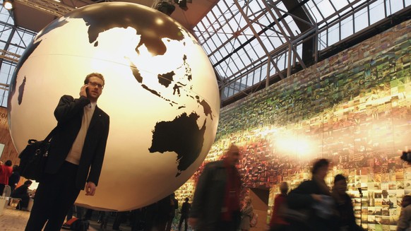 File - In this Tuesday Dec. 15, 2009 file photo, a man speaks on his cell phone in front of a giant globe in Copenhagen. As of Thursday, June 15, 2017, European Union holiday makers can return home wi ...