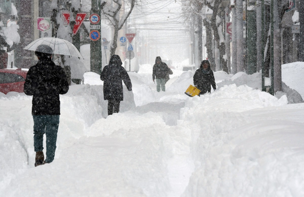epa11875694 People walk in a street covered with snow following heavy snowfall in Obihiro, Hokkaido, northern Japan, 04 February 2025 (issued 05 February 2025). On 05 February 2025, the coldest air of ...