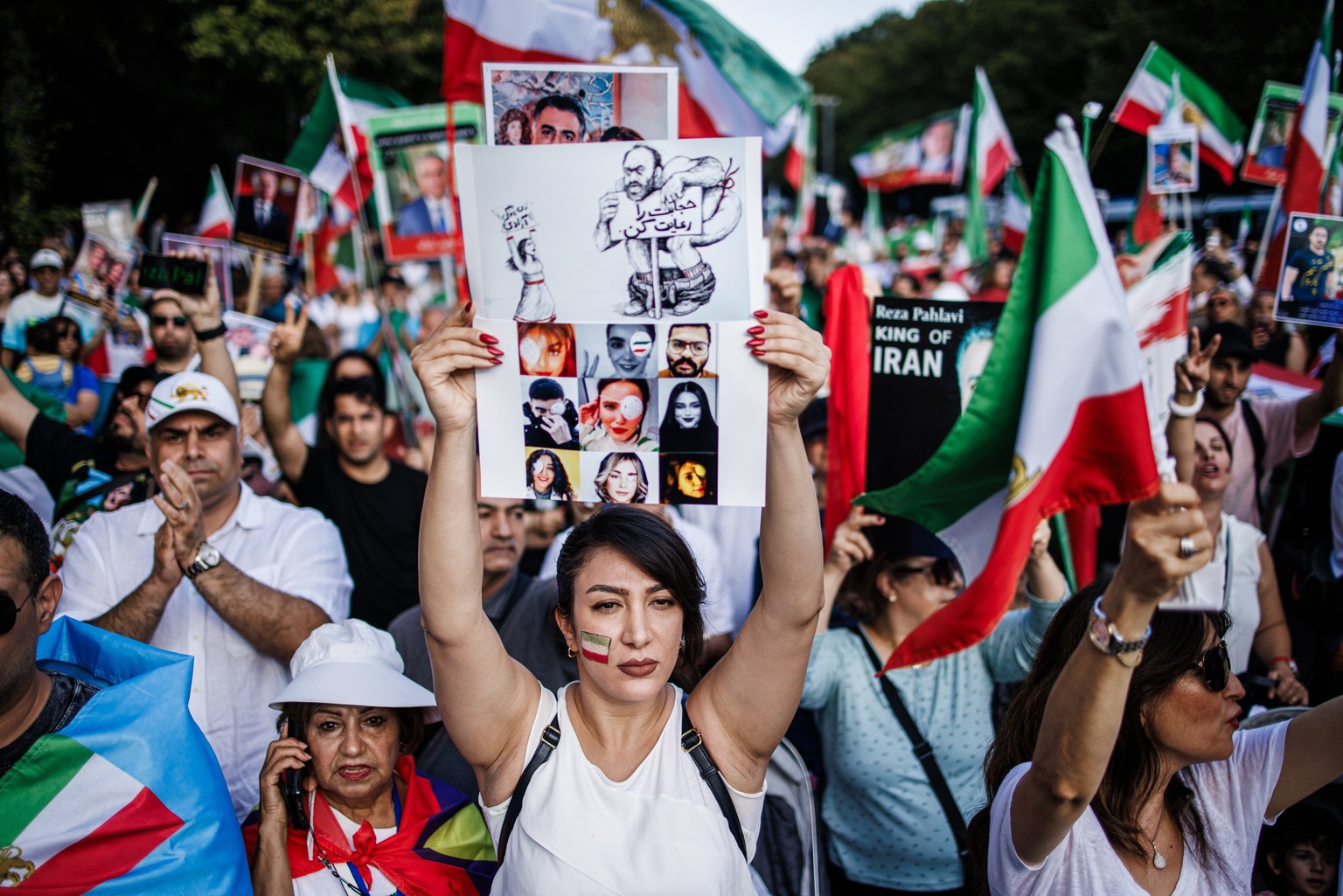 epa10864635 A demonstrator holds a sheet showing photos of victims, among them Jina Mahsa Amini during a rally at the anniversary of the death of Jina Mahsa Amini in Berlin, Germany, 16 September 2023 ...