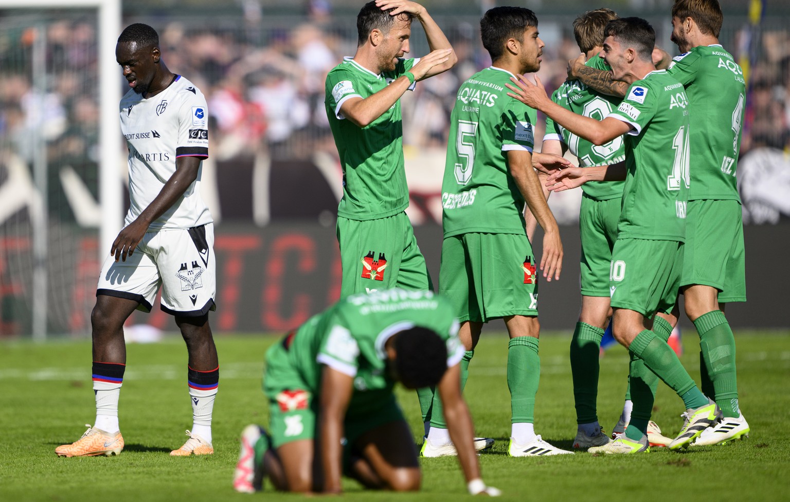 Les joueurs yverdonnois celebrent la victoire devant la deception de l&#039;attaquant balois Jean-Kevin Augustin, gauche, a la fin de la rencontre de football de Super League entre le Yverdon Sport FC ...