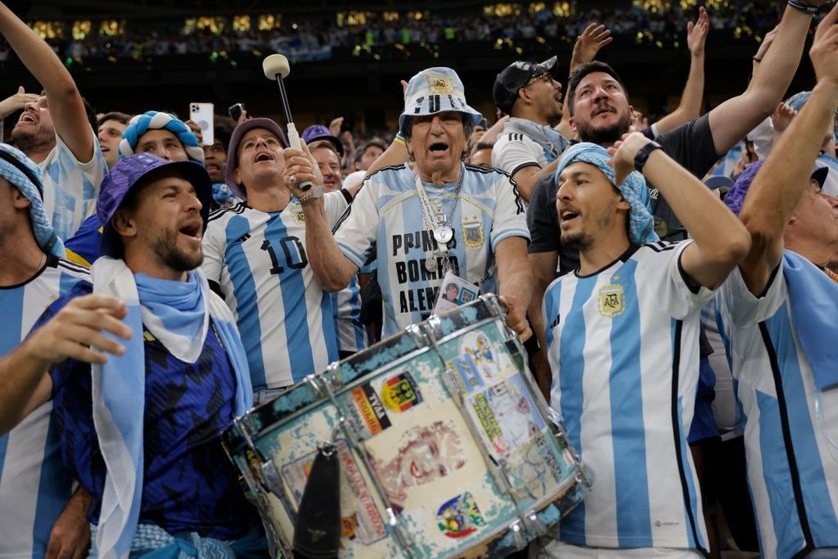 Carlos Pascual, otherwise known as El Tula, an 82 year-old Argentinian drummer, at his thirteenth World Cup, is flanked by his sons as he bashes his drum given to him by Juan Peron, and featuring imag ...