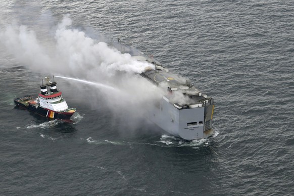 A boat hoses the smoke from a fire which broke out on a freight ship in the North Sea, about 27 kilometers (17 miles) north of the Dutch island of Ameland, Wednesday, July 26, 2023. A fire on the frei ...