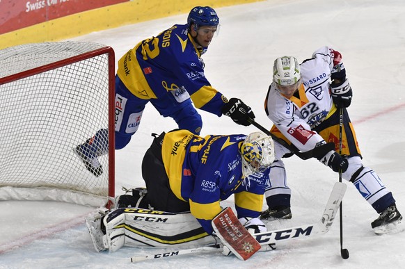 Der Zuger Jarkko Immonen, rechts, testet die Davoser Abwehr mit Felicien Du Bois, links, und Torhueter Joren van Pottelberghe, waehrend dem Eishockey-Qualifikationsspiel der National League A zwischen ...