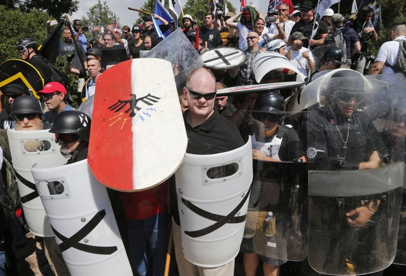 FILE - In this August 12, 2017, file photo, white nationalist protesters use shields as they guard the entrance to Lee Park in Charlottesville, Virginia.  They want to avoid the chaos that has broken out at Gat...