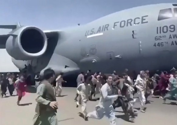 Some hundreds of people run alongside a U.S. Air Force C-17 transport plane as it moves down a runway of the international airport, in Kabul, Afghanistan, Monday, Aug. 16. 2021. Thousands of Afghans h ...