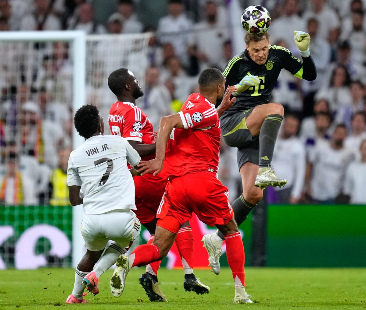 Bayern's goalkeeper Manuel Neuer heads the ball to save before Real Madrid's Vinicius Junior, left, can score during the Champions League quarterfinal first leg soccer match between Real Mad ...