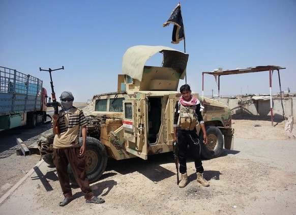 Kämpfer der ISIS-Dschihadisten posieren vor einem US-Humvee.