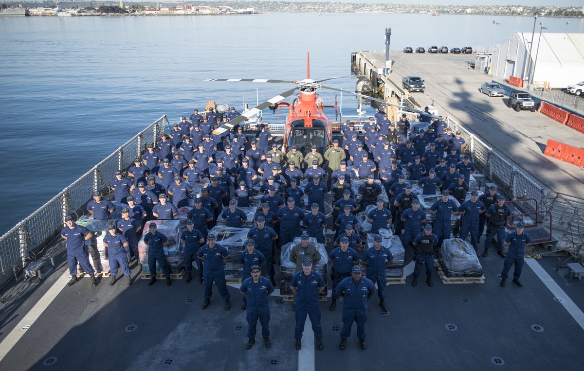 epa06616853 A handout photo made available by the US Coast Guard shows the crew of the Coast Guard Cutter Bertholf (WMSL-750) standing at attention near seized cocaine on the cutter's flight deck ...