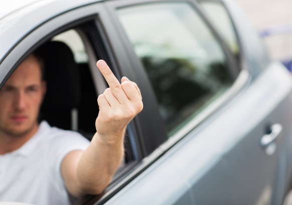 Mann zeigt im Auto den Stinkefinger