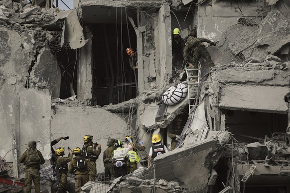 Israeli soldiers and rescue workers carry a body from a residential building destroyed by an Iranian missile strike that killed several people, in Beersheba, Israel, on Tuesday, June 24, 2025. (AP Pho ...
