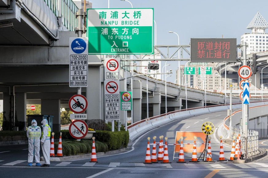 Polizisten in Schutzkleidung bewachen eine Rampe zur Brücke, die über den Huangpu-Fluss in den Stadtteil Pudong führt, nachdem der Verkehr während der Abriegelung eingeschränkt wurde.