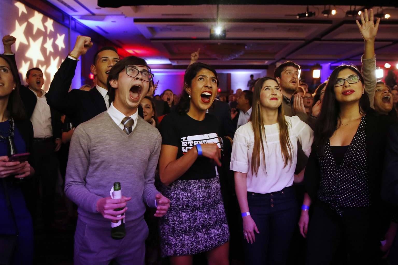 Jed Bush, 24, left, of Washington, a Hill staffer, Maria Praeli, 25, a DACA recipient, and Katie Aragon, 26, react to Democratic wins in the House of Representatives, during a Democratic party electio ...