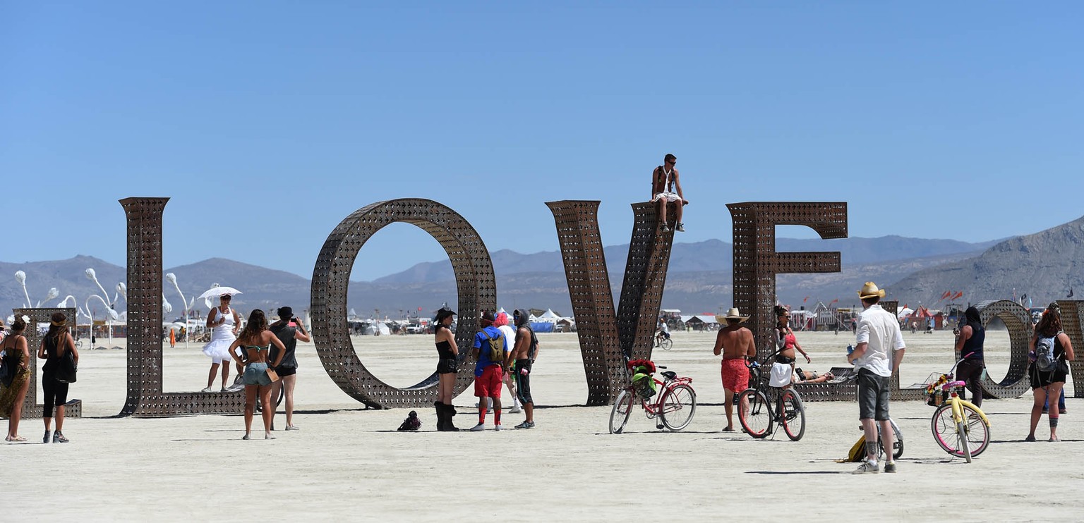 In this Aug. 27, 2014 photo, participants walk around at the Burning Man festival on the Black Rock Desert of Gerlach, Nev. Organizers call Burning Man the largest outdoor arts festival in North Ameri ...