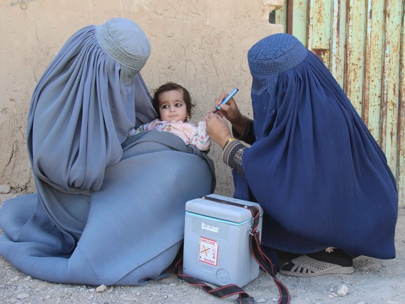 epaselect epa08887272 Afghan health workers administer polio vaccination to a child in Kandahar, Afghanistan, 16 December 2020. Vaccination campaign in Afghanistan resumed after seven months of break  ...