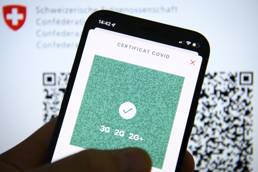 Une personne tient dans sa main un smartphone avec l&#039;application Certificat Covid suisse et son code QR indiquant 3G, 2G et 2G+ ce mercredi 12 janvier 2022 a Lausanne. (KEYSTONE/Laurent Gillieron ...