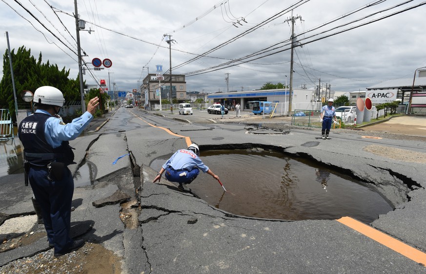 epa06817616 Workers check damage of a road collapsed by an earthquake in Takatsuki, Osaka Prefecture, western Japan, 18 June 2018. The earthquake, which struck western Japan, killed three people injur ...