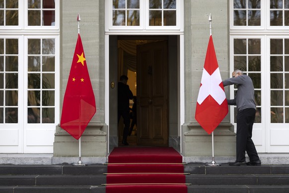 epa11078829 A worker prepares the flags ahead of the arrival of the Swiss President and the Chinese Prime Minister, in Kehrsatz near Bern, Switzerland, January 15, 2024. The Chinese Prime Minister ...