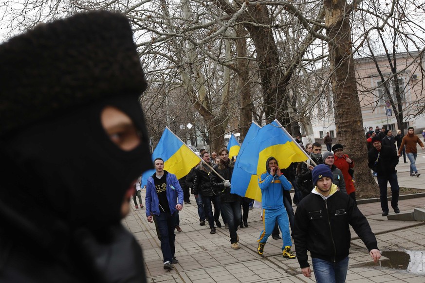 Ein Mitglied der prorussichen Milizen auf der Krim (l.) beobachtet den Aufmarsch von proukrainischen Demonstranten in der Regionalhauptstadt Simferopol.&nbsp;