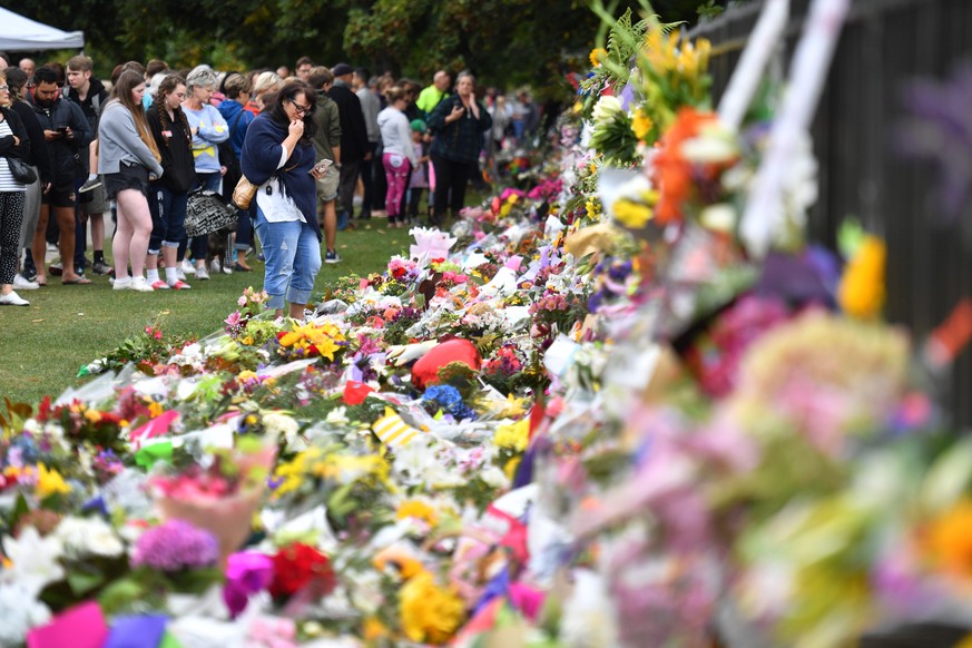 epa07443997 Members of the public place flowers at a makeshift memorial for the victims of the mosque mass murders at the Botanical Gardens in Christchurch, New Zealand, 17 March 2019. A gunman killed ...