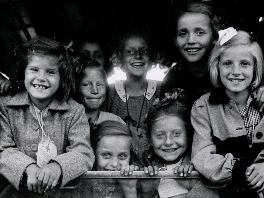 Zugkinder schauen im Sommer 1947 vor der Abfahrt in die Schweiz aus dem Zugfenster in Berlin.