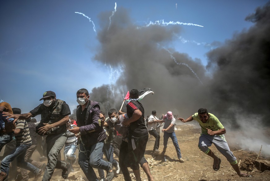 epa06737540 Palestinian protesters run for cover from Israeli tear-gas during clashes after protests near the border with Israel in the east of Gaza Strip, 14 May 2018 (issued 15 May 2018). More prote ...