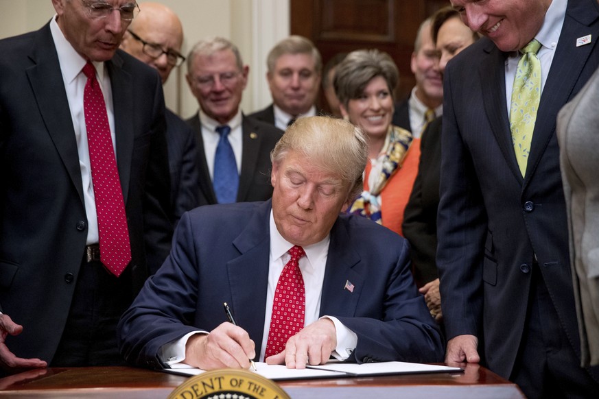 President Donald Trump signs the Waters of the United States (WOTUS) executive order, Tuesday, Feb. 28, 2017, in the Roosevelt Room in the White House in Washington, which directs the Environmental Pr ...