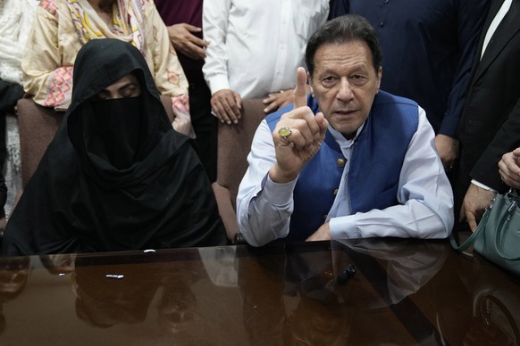 FILE - Pakistan&#039;s former Prime Minister Imran Khan, right, and Bushra Bibi,his wife, speak to the media before signing documents to submit surety bond over his bails in different cases, at an off ...