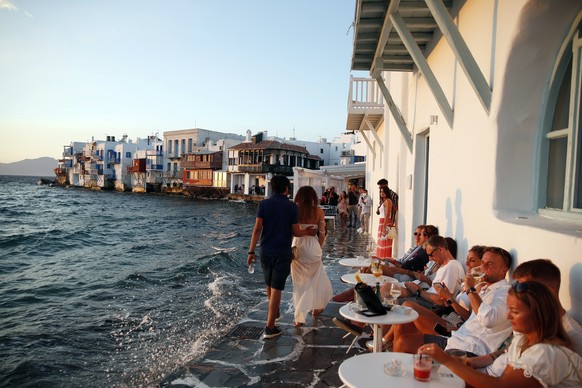 People sit at a bar in Little Venice on the Aegean Sea island of Mykonos, Greece, Sunday, Aug. 16, 2020. Wary of a rise in daily coronavirus cases that threatens to undo its relative success in contai ...