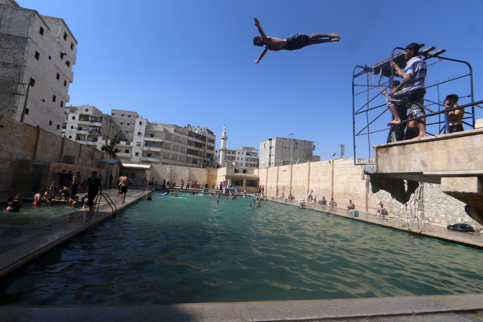 Auch das gibt es im Bürgerkriegsland: Ein Junge springt in der seit Jahren heftigst umkämpften Stadt Aleppo in einen Swimming Pool&nbsp;– die Aufnahme datiert von dieser Woche.