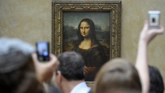 epa02673616 Visitors crowd and take pictures of Leonardo da Vinci&#039;s painting La Gioconda (Mona Lisa), at the Louvre Museum in Paris, France, 07 April 2011. Italian researchers have announced on 0 ...