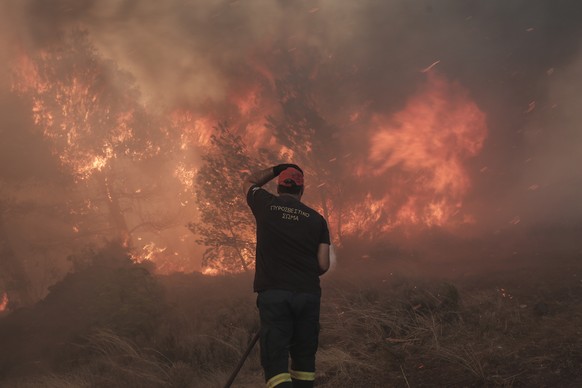 epa10813688 A firefighters reacts while battling flames of a wildfire at the area of Fyli near Athens, Greece, 22 August 2023. A wildfire is in progress in Fyli, west Attica region. So far, 26 firefig ...